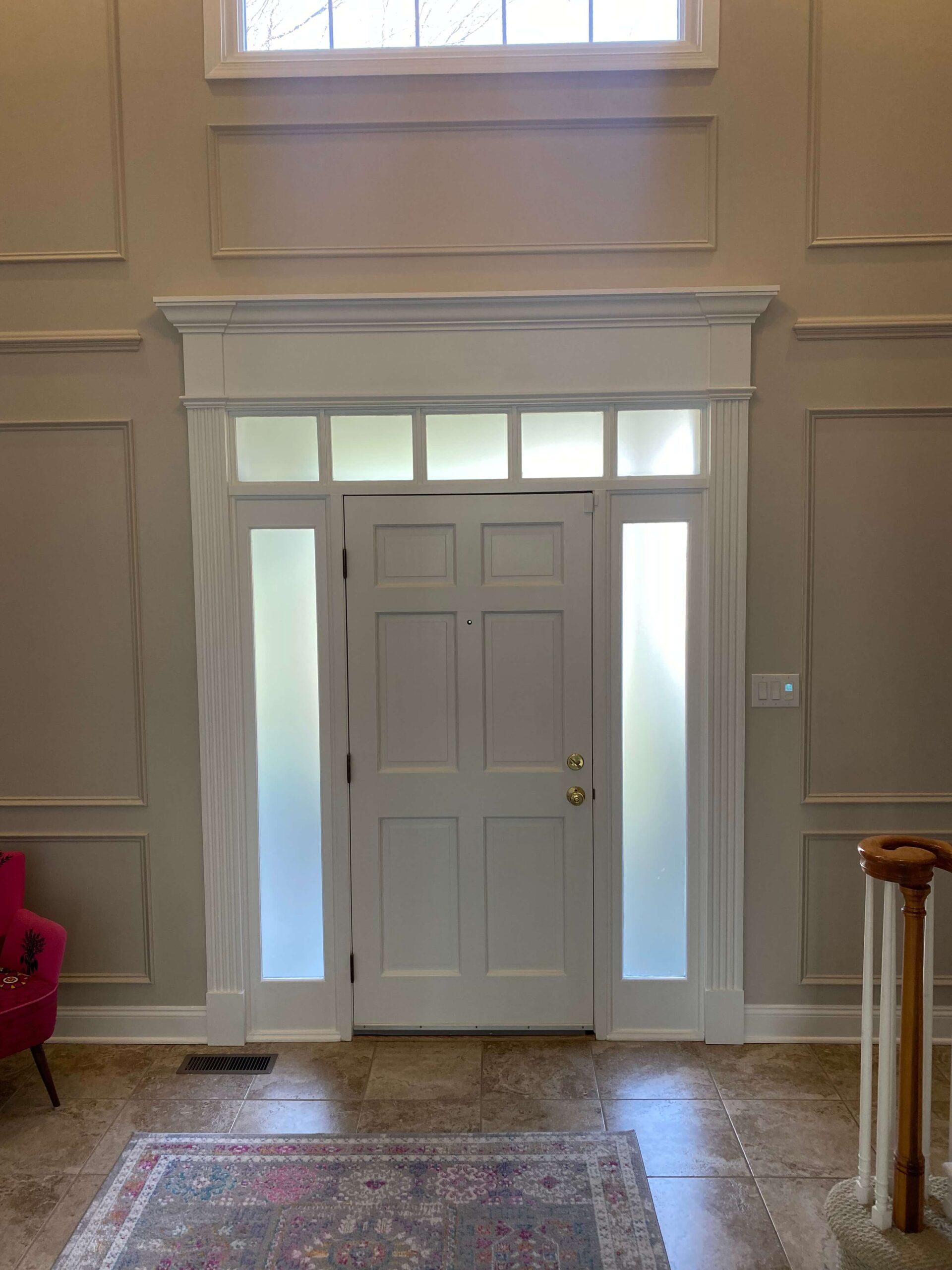 Custom front door trim work, with accented wall panel and custom fabricated window trim.