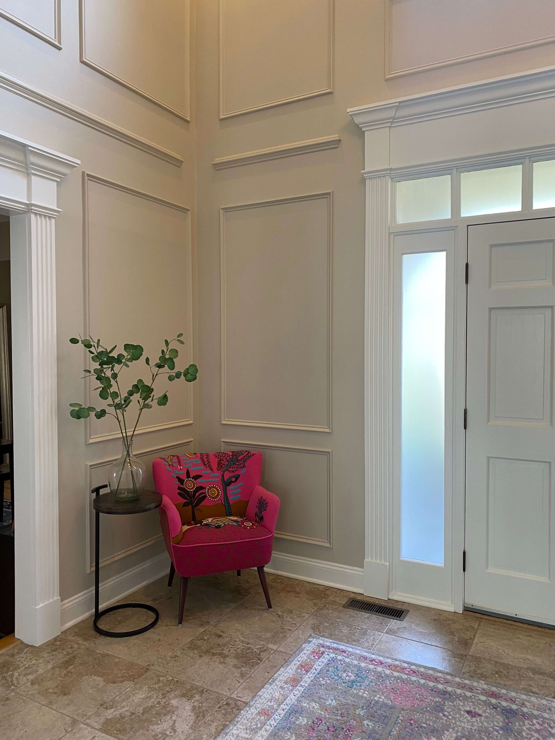 Two-story foyer with custom paneled walls, custom trim work, new doorway headers, and accented front door.